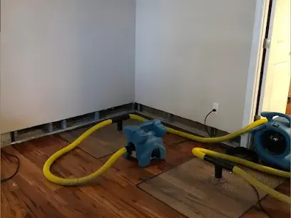 Air movers along a wall with the baseboards removed on a wood floor