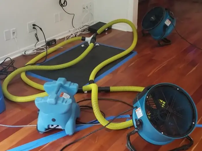 Floor drying mats and air movers set on a wet hardwood floor
