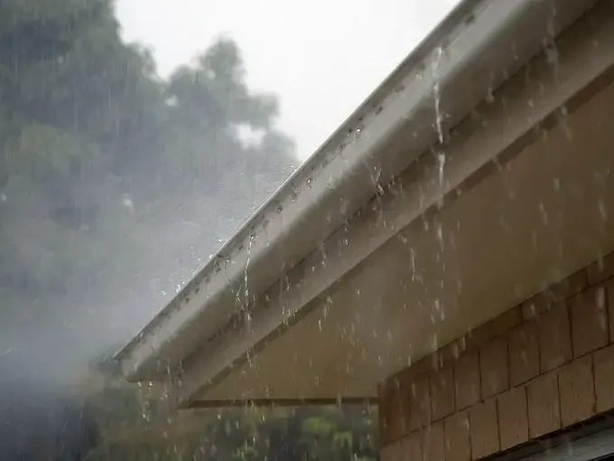 Heavy winter rain pouring off a roof edge